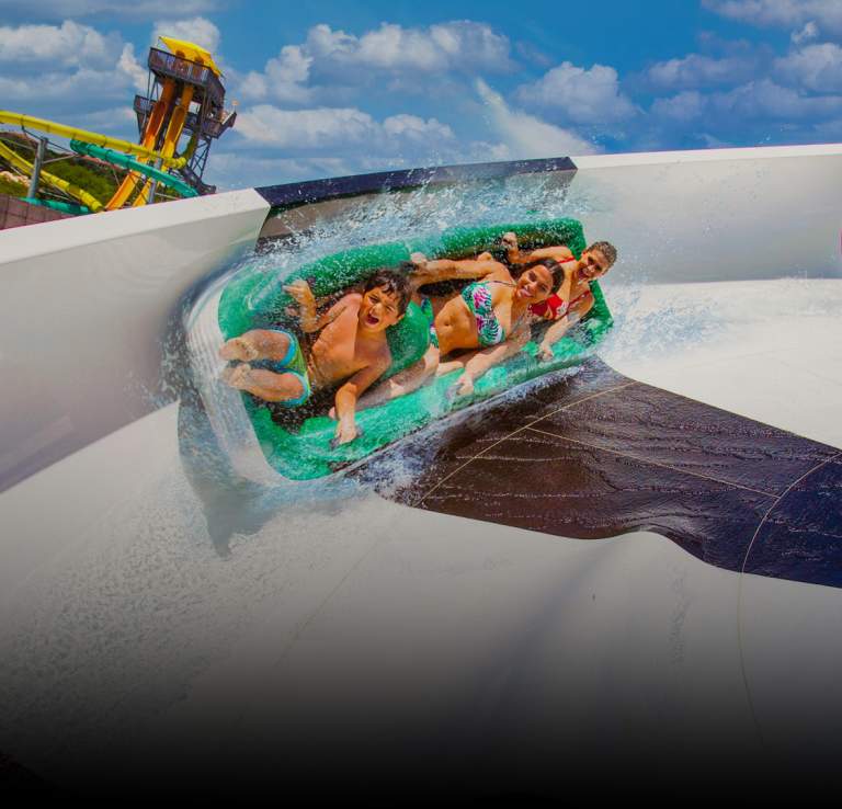 People on waterslide with dark gradient overlay.