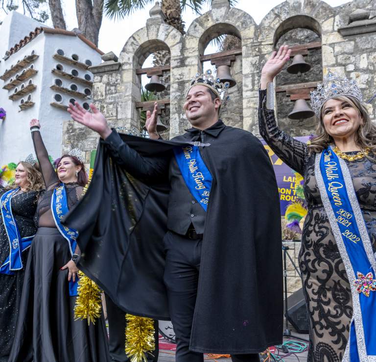 People dressed in costumed royalty waving to crowd at Arneson River Theatre.