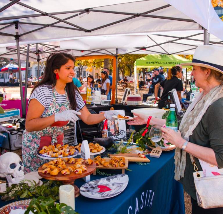 Woman handing plate of food to festival goer