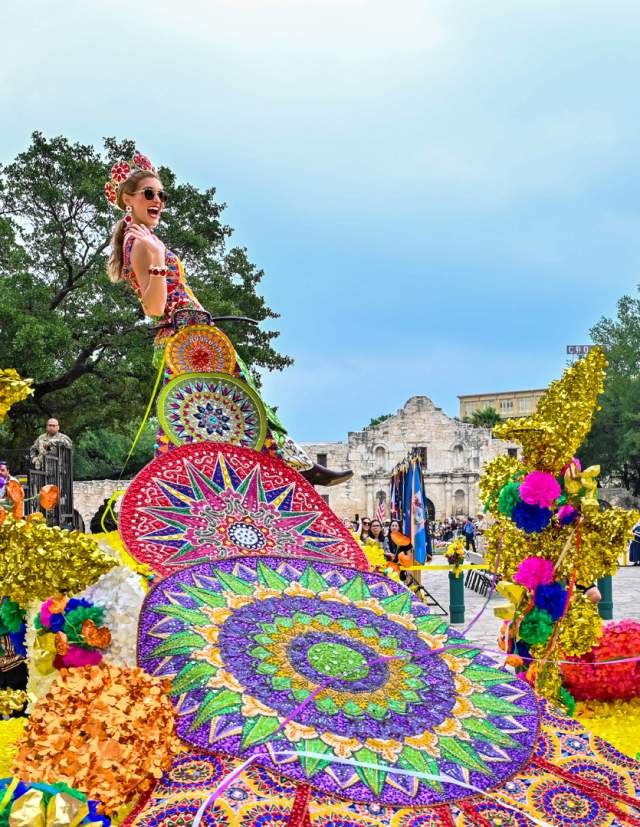Parade participants on float dressed in elaborate dresses at Battle of Flowers parade in San Antonio in Fiesta San Antonio.