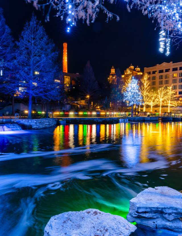 Museum Reach portion of River Walk lit up with blue-hued holiday lights.