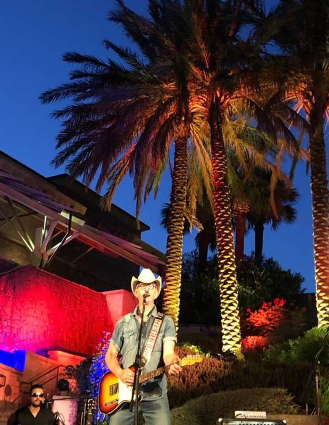 Two Tons of Steel playing in front of shopping center and palm trees.