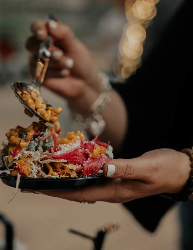 Person's hands holding plate of food and spoon.