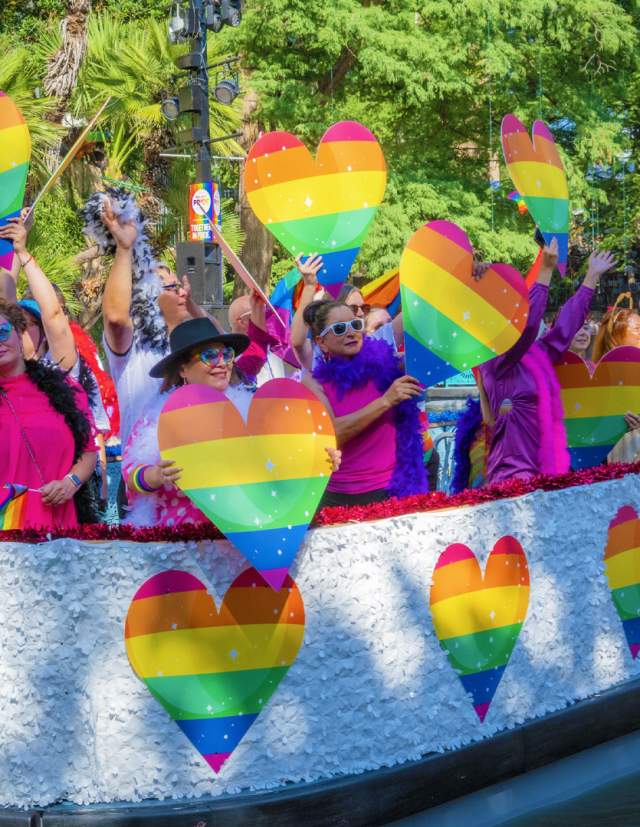 River barge with rainbow hearts and people floating on River Walk