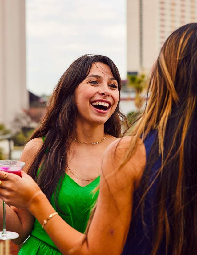 Two girls holding drinks and laughing