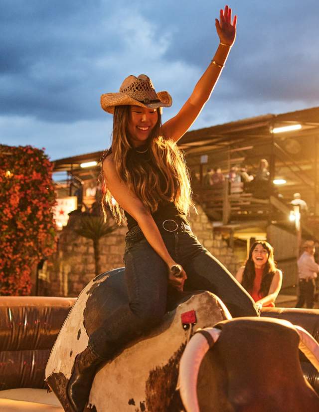 Girl on mechanical bull at Tejas Rodeo