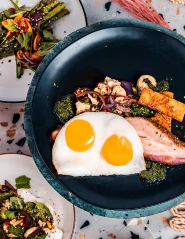 Overhead view of bowl will over easy egg and side salads