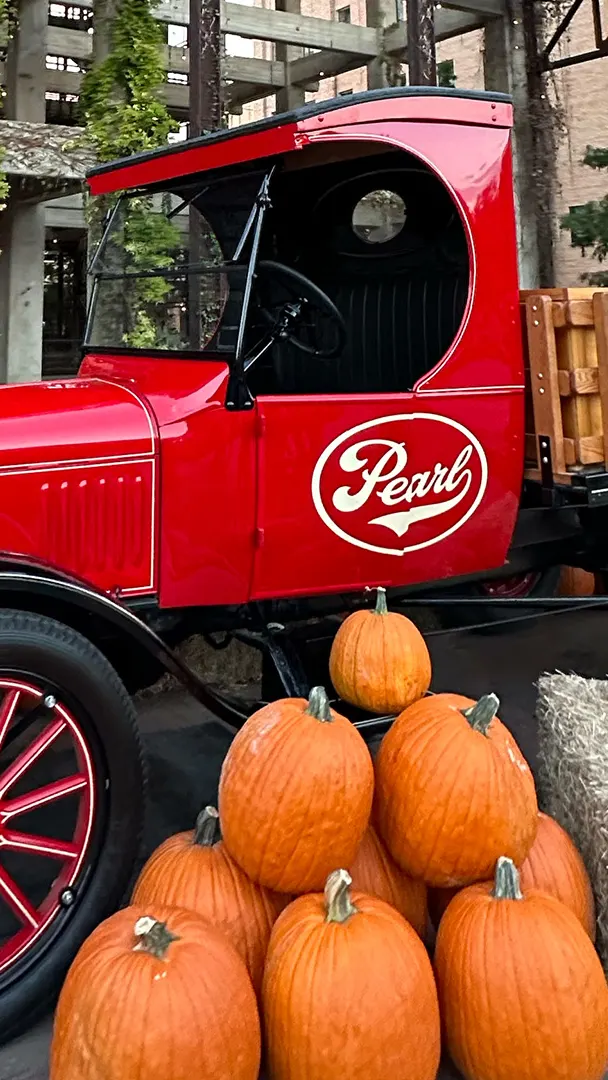 Red truck with Pearl logo surrounded by pumpkins and hay.