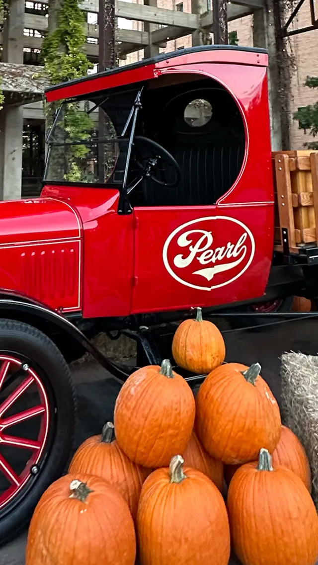 Red truck with Pearl logo surrounded by pumpkins and hay.
