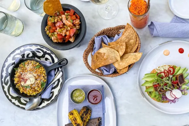 Overhead view of food spread with skillet corn, chips, and plated meal