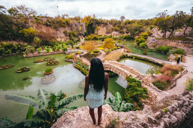 Woman overlooking lush garden and standing water at Japanese Tea Garden.