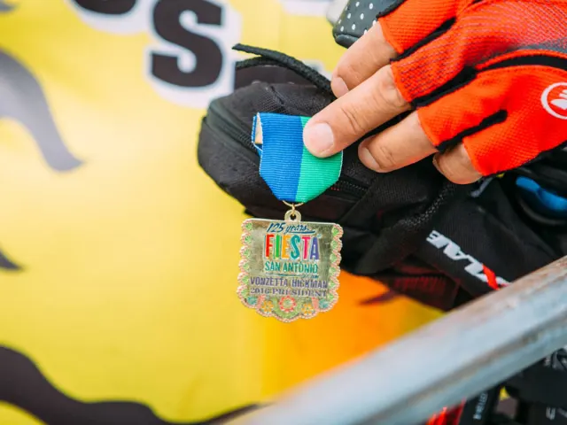 Cyclist holding fieta medal in San Antonio.