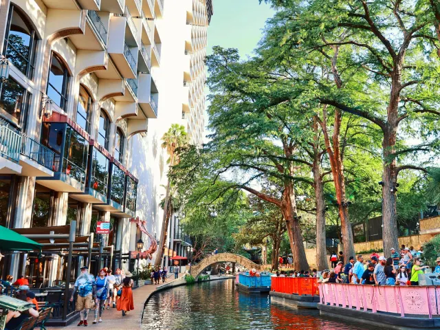 River barges on San Antonio River Walk floating by hotels.