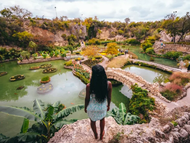 Woman overlooking lush garden and standing water at Japanese Tea Garden.