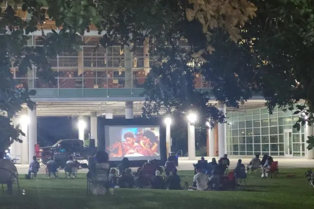 People watching film outside on projector