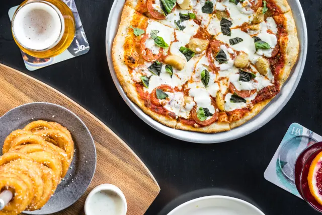 Overhead view of food spread, including onion rings and pizza.