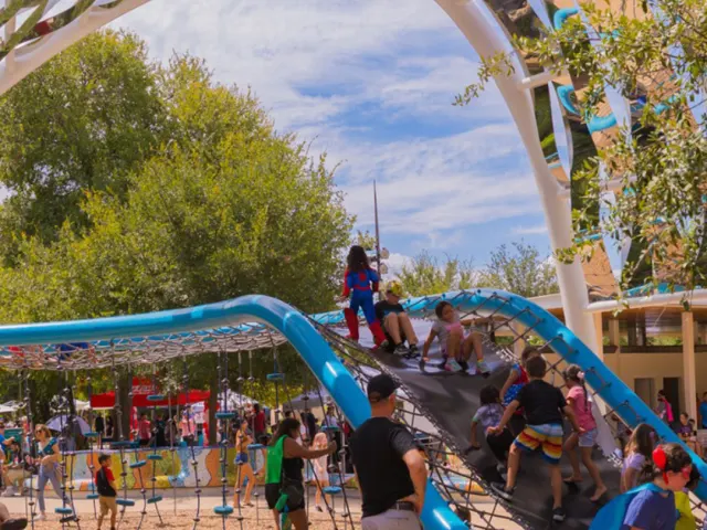 Children and families playing on outdoor blue play structure.