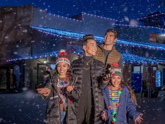 Family laughing with snow falling at San Antonio Zoo's Zoo Lights.