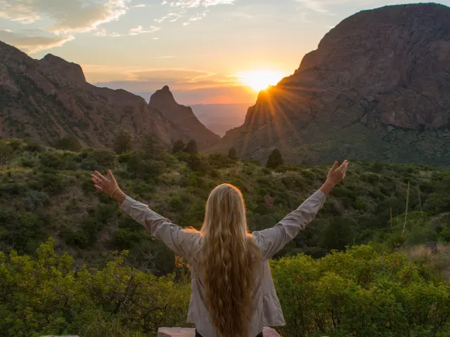 Girl with arms open overlooking sunset and valleys