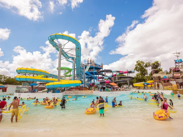 Panoramic view of waterpark with people walking with inner tubes.