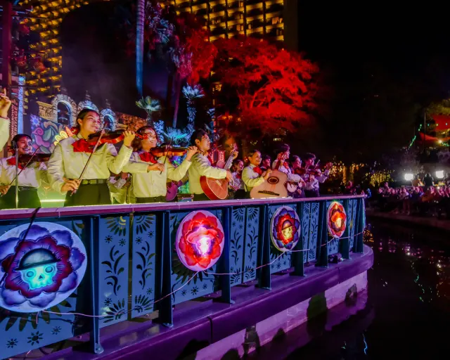 Mariachi band members on a river barge drifting in the Day of the Dead River Parade.