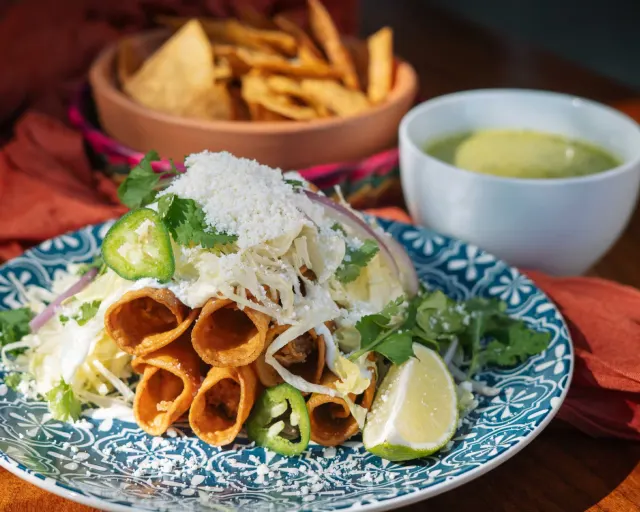 Plate of flautas topped with jalepenos and lime from Mexico Ceaty in San Antonio.
