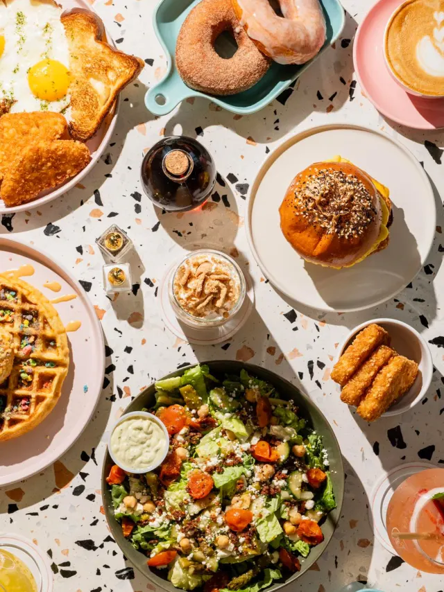 Overhead view of breakfast spread with waffles and donuts.