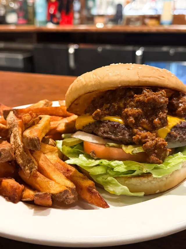 Hamburger with lettuce and fixings on a plate with french fries.