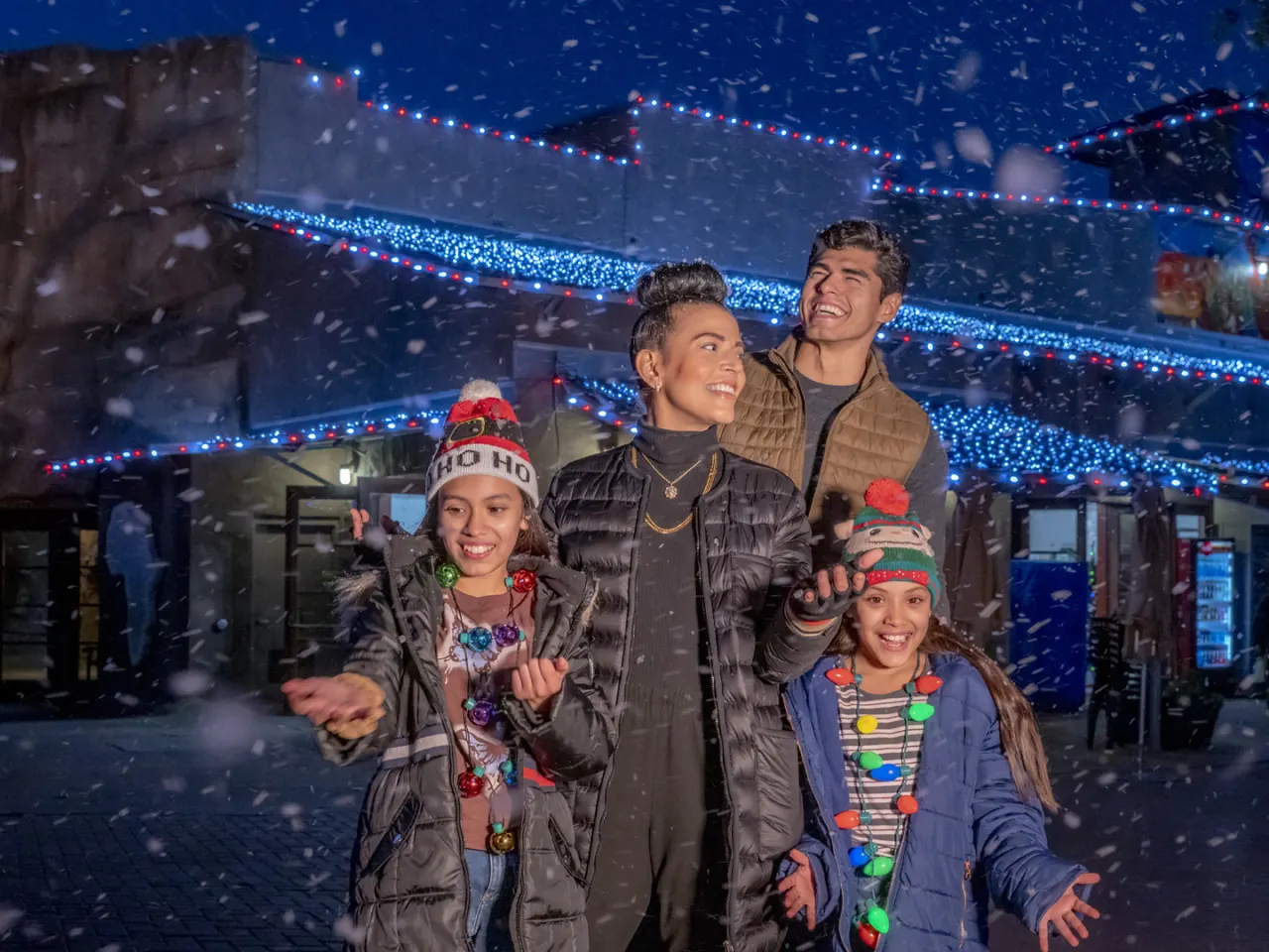 Family laughing with snow falling at San Antonio Zoo's Zoo Lights.