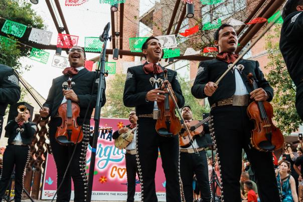 Mariachis standing in front of papel picado