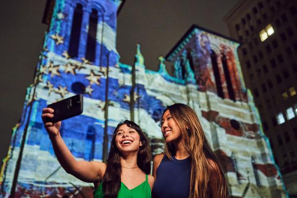 Two girls in front of light show projection