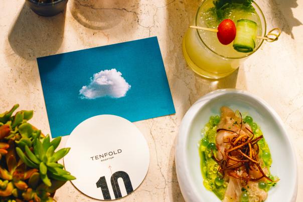 Overhead view of food and drink spread with a coaster from Tenfold Rooftop bar.