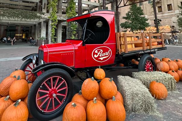 Red truck with Pearl logo surrounded by pumpkins and hay.