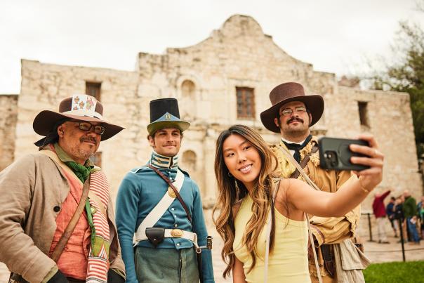 Girl taking a selfie with Alamo staff in costume