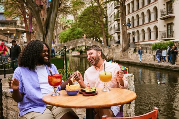 Two men on the River Walk enjoying chips and margaritas