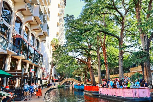 River barges on San Antonio River Walk floating by hotels.