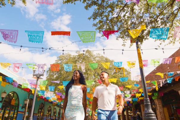 Couple walking through Historic Market Square with papel picado above them