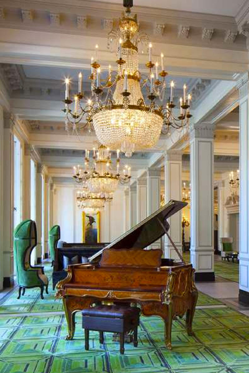 Lobby of St. Anthony hotel in San Antonio with piano and chandelier.