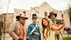 Girl taking a selfie with Alamo staff in costume