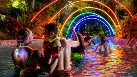 People wading under colorful lights at night.