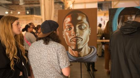 Man and woman viewing portait of a man at a gallery at DreamWeek San Antonio.