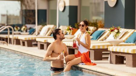 Man and woman drinking cocktails poolside at Hotel Contessa.