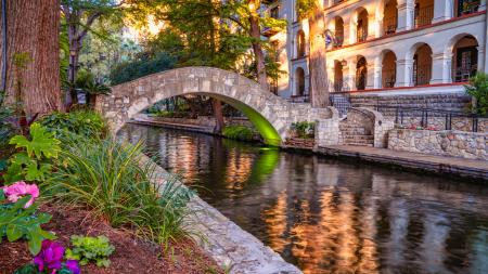 Bridge at San Antonio River Walk with flowers and Omni La Mansion del Rio hotel in background.