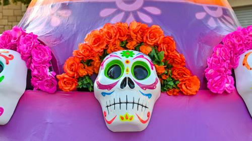 Brightly colored sugar skills with pink and orange flowers aranged around their heads at La Villita in San Antonio.