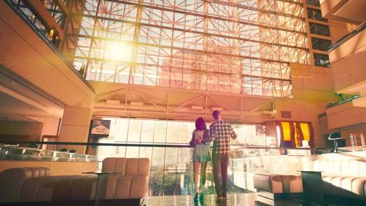 Man and woman looking at hotel lobby with bright sun shining through window.