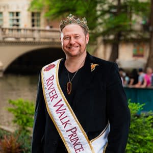 man posing taking photo by river walk wearing Prince royalty sash