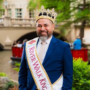 man posing in navy suit with King royalty sash