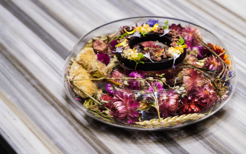 Circular plate of food adorned with florals at Nicosi restaurant in San Antonio.