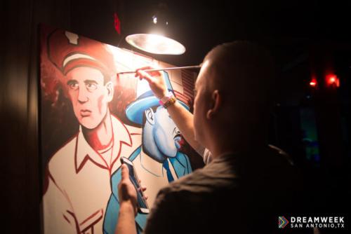man painting in the dark with an overhead lamp