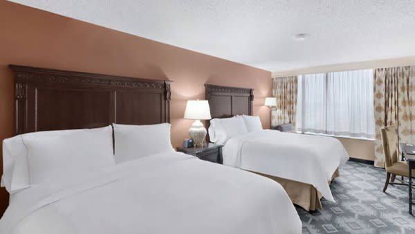 Two hotel beds in hotel room with curtains.